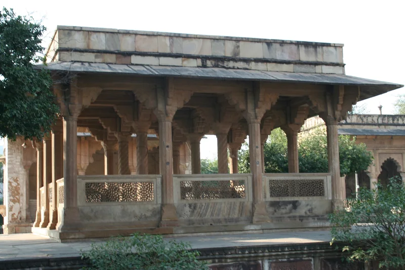 ग्वालियर में तानसेन के मकबरे का छोटा समतल छत वाला मंडप, स्तंभों के बीच पत्थर की जालियाँ